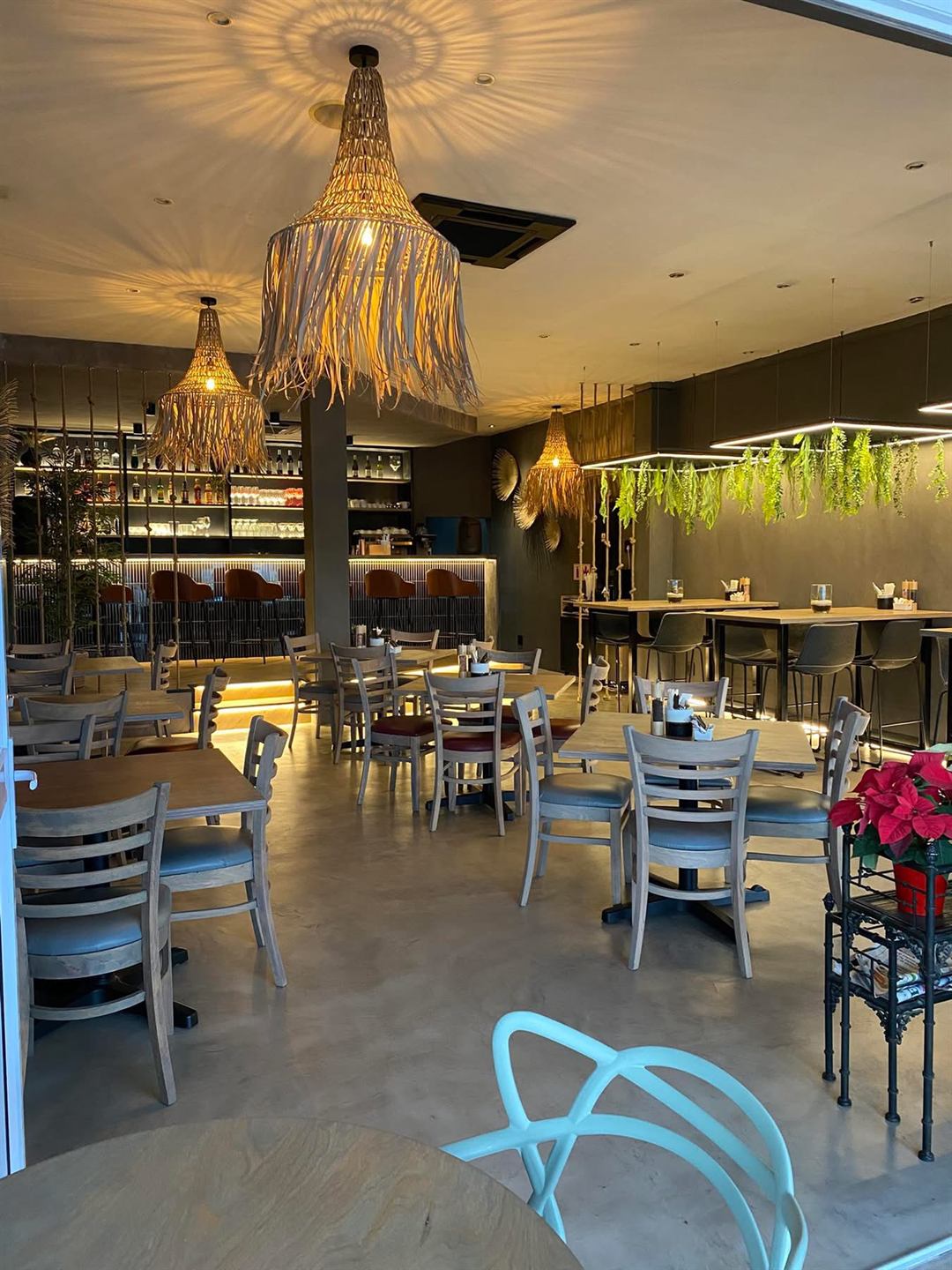 Inside BRÜ Restobar: woven rattan pendant lights, timber tables, hanging greenery and a softly lit bar