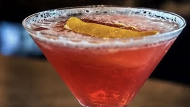 Cosmo Rouge cocktail in a martini glass with an orange twist